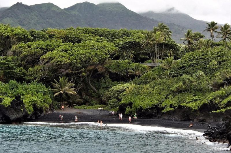 Waianapanapa State Park, located along the scenic Hana Highway, features one of Maui's most beautiful black sand beaches